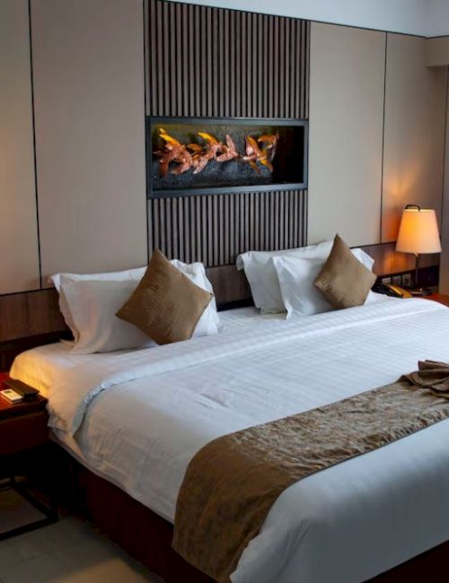 A neatly arranged hotel room with a large bed, two bedside tables, lamps, artwork above the headboard, and a table with a chair.