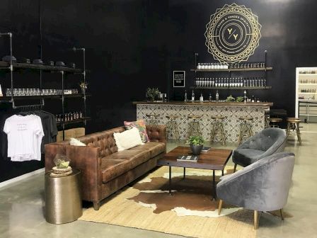 The image shows a modern lounge with a brown leather sofa, two grey chairs, a coffee table, and a decorated bar counter.