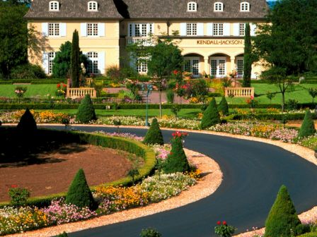 A grand mansion with landscaped gardens and a curved driveway, featuring the name 