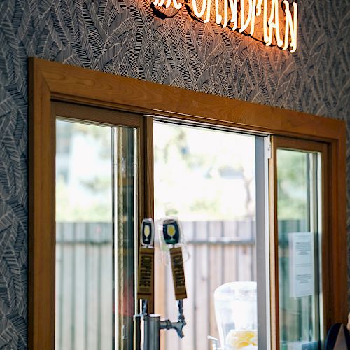 A bar area with beer taps, a window, and a neon sign that reads 