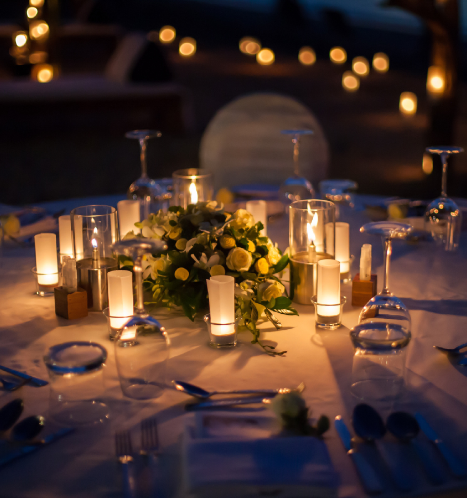 A beautifully set dinner table with candles, flowers, and place settings, creating a romantic and intimate atmosphere.